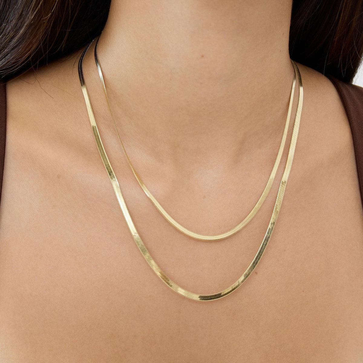 14K yellow gold herringbone chain necklaces layered, two lengths worn on a woman's neck, front view