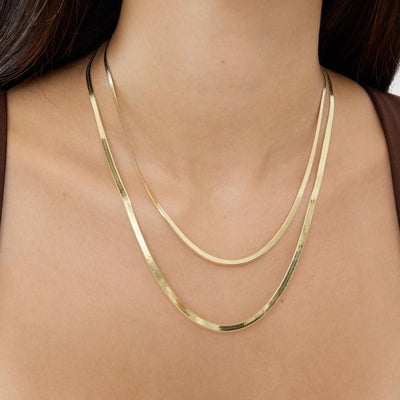 14K yellow gold herringbone chain necklaces layered, two lengths worn on a woman's neck, front view