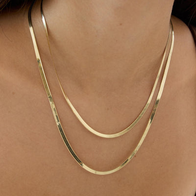 14K yellow gold herringbone chain necklaces, two layered strands worn close up on the neck and collarbone