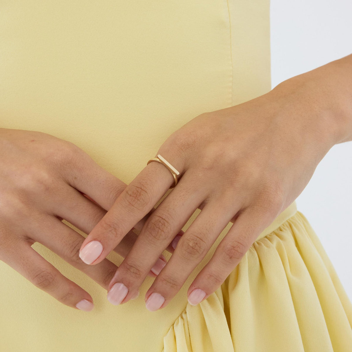 14K gold horizontal bar ring worn on finger resting on opposite hand