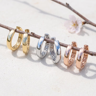 14K huggie hoop earrings in yellow, white and rose gold, three pairs hanging on a branch