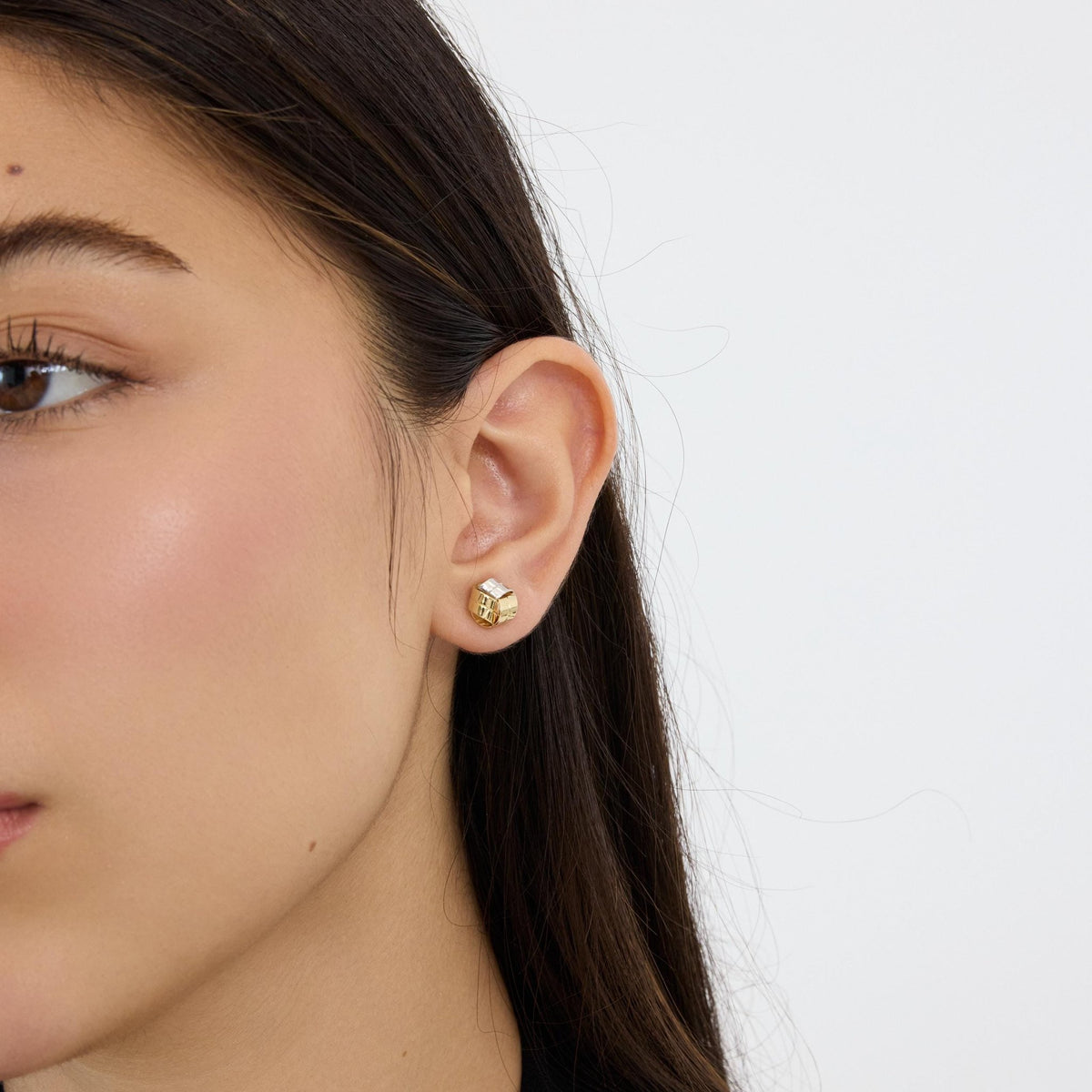 14K gold knot stud earring worn on ear, model facing slightly forward on plain white background