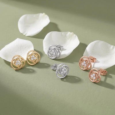 14K love knot stud earrings with cubic zirconia in yellow, white and rose gold, three pairs on petals