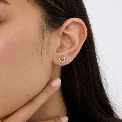 14K gold open heart stud earring with round cubic zirconia worn in the ear, close side profile