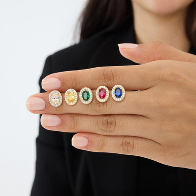 14K gold oval stud earrings in five stone colours lined up on a woman's hand, close view