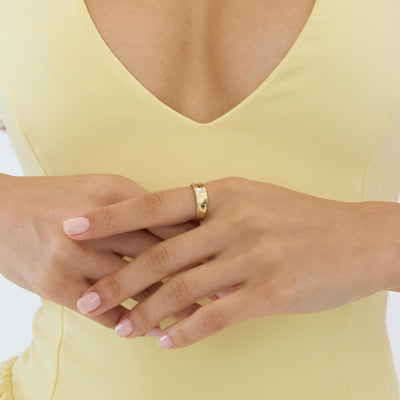 14K gold plain band ring styled on a neutral backdrop, sixth angle