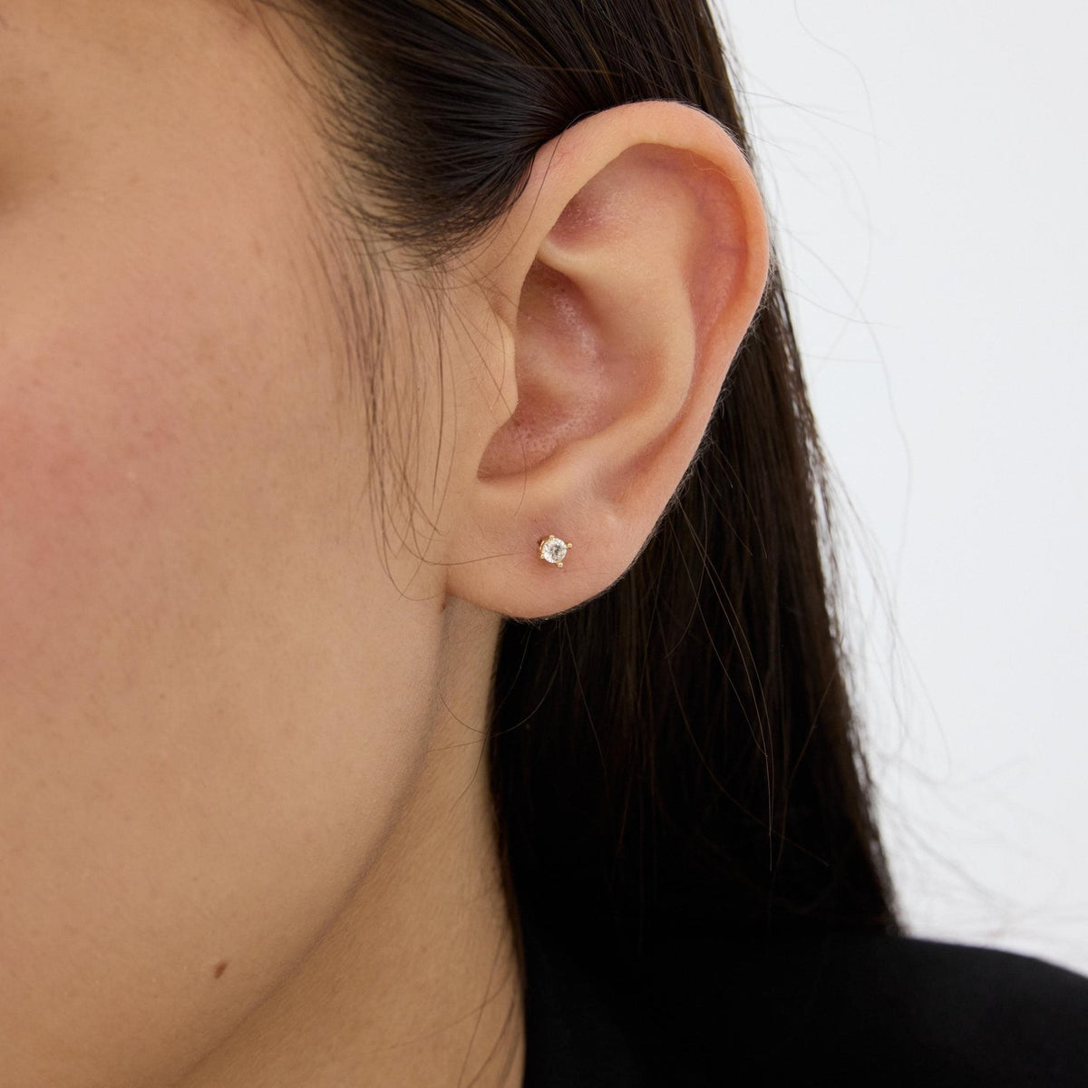 14K gold round cubic zirconia solitaire stud earring worn in the ear lobe, side view of the ear