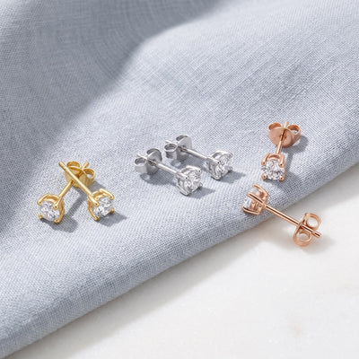 14K round cubic zirconia solitaire stud earrings in yellow, white and rose gold, three pairs on grey linen
