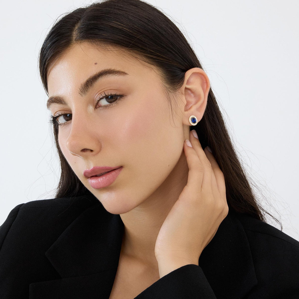 14K gold round halo stud earring with simulated sapphire worn on ear, model touching neck