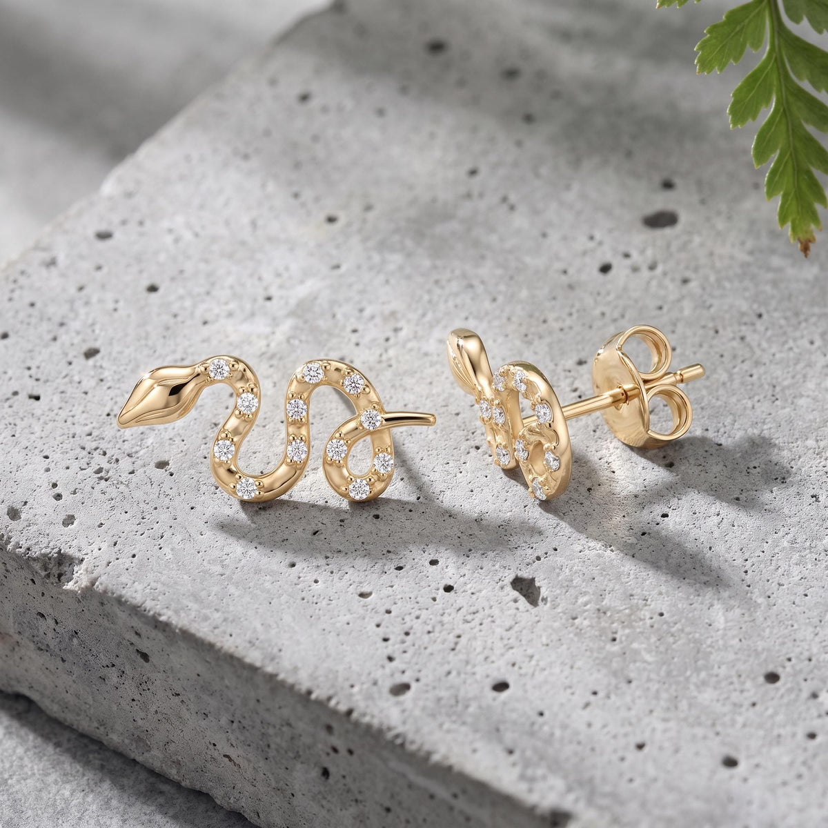 14K gold snake stud earrings styled on a neutral backdrop
