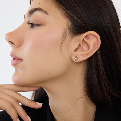 14K gold snake stud earrings styled on a neutral backdrop, fifth angle