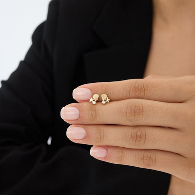 Pair of 14K gold starfish stud earrings with cubic zirconia on a hand, small scale against fingers