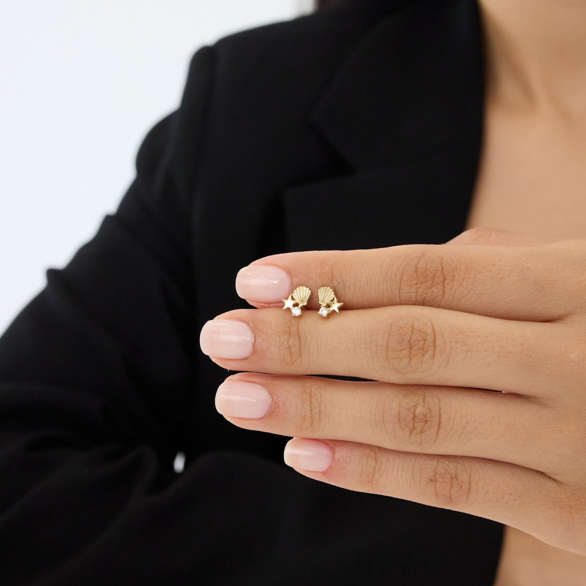 14K gold starfish stud earrings with cubic zirconia on fingertips, second hand-held scale view