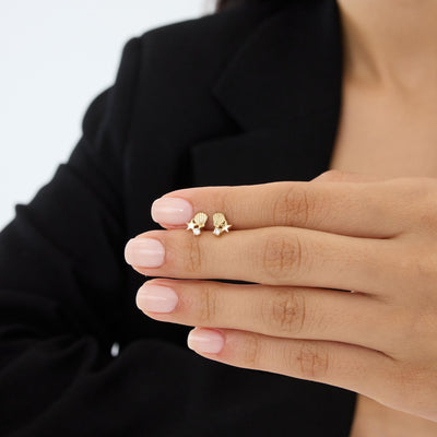 14K gold starfish stud earrings with cubic zirconia resting on fingers, third hand-held view