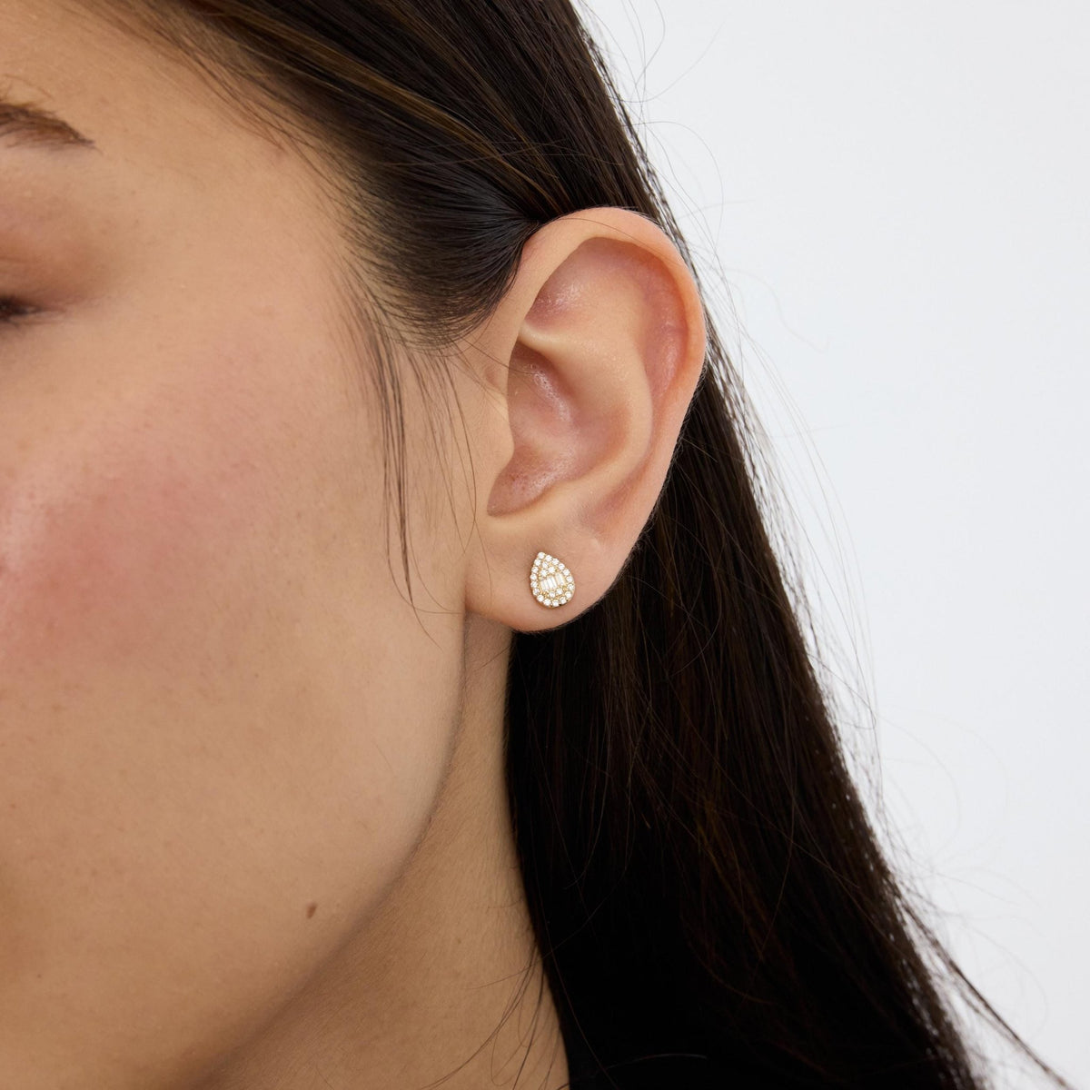 14K gold teardrop stud earrings styled on a neutral backdrop, third angle