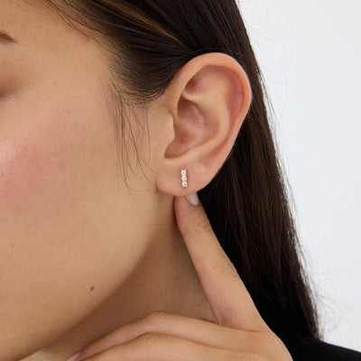 14K gold three stone cubic zirconia stud worn on the ear lobe, model touching neck, second angle